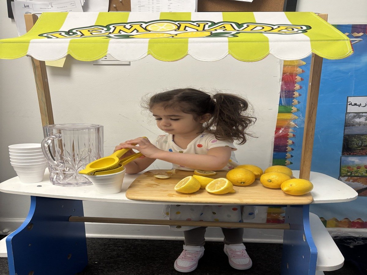 Preschooler at Iqra Learning engaging in pretend play with a classroom lemonade stand setup